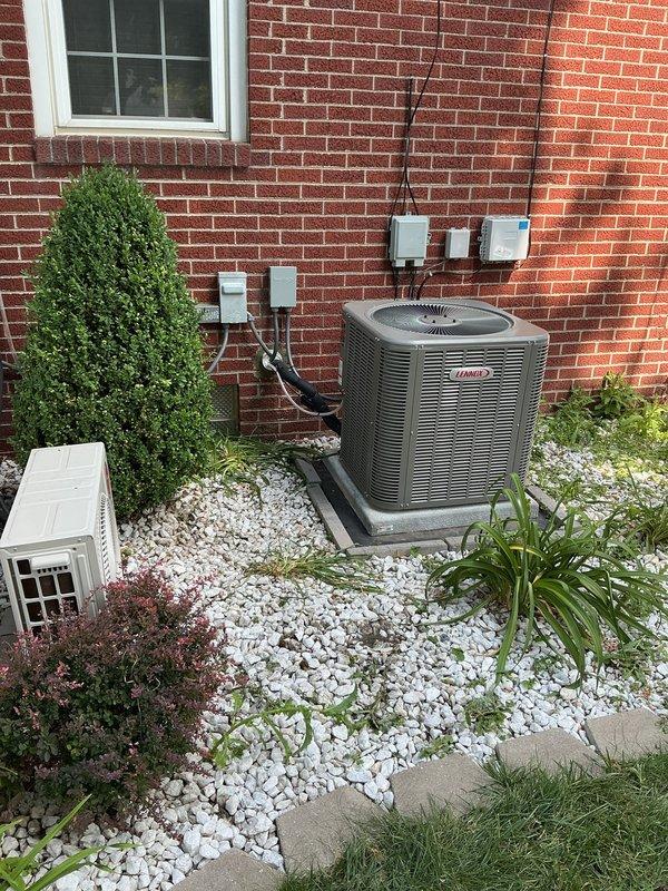 Completed full split system HVAC installation featuring a Lennox single-stage condenser unit positioned on a composite pad with white decorative rock landscaping against the brick exterior, and an upflow air handler installed in the basement utility area. Fabricated custom return base with 5-inch rack, ran new supply and return drops, installed 3/4-inch by 20-foot lineset with proper insulation, mounted electrical disconnect and whip, and added outdoor surge protection for equipment longevity. Ran dedicated electrical circuit to outdoor unit while tying into existing service, replaced thermostat for system control, and ensured all refrigerant lines, electrical conduit, and ductwork connections were properly secured and code-compliant.