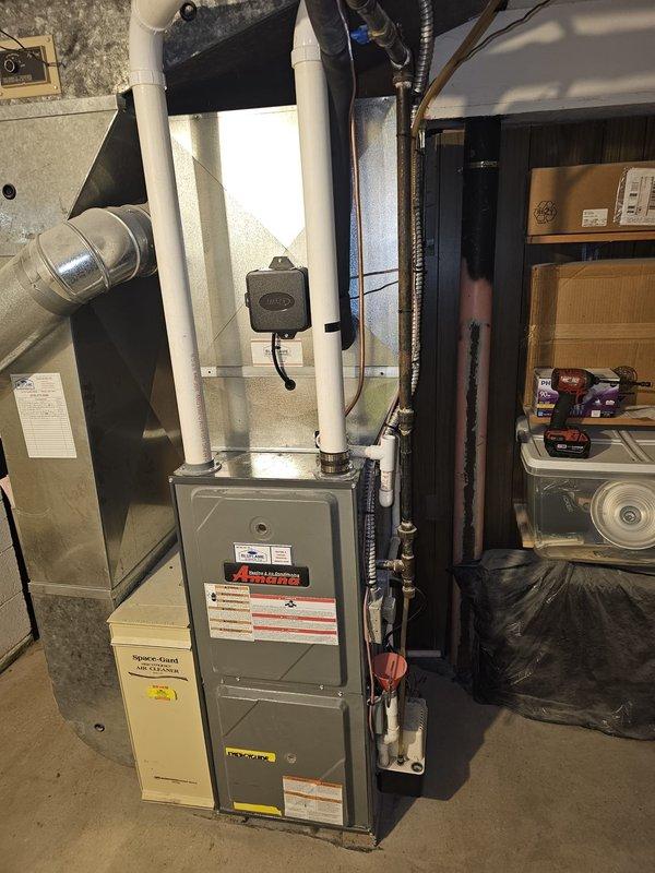 Completed full HVAC system installation in basement utility area, including new air conditioning unit with matching upflow cased coil package. Installed new 3/4" x 30' refrigerant line set with proper insulation and routing. Set new outdoor condenser pad with level placement and positioned unit for optimal airflow and service access. Ran new electrical disconnect and whip to outdoor unit per code requirements. Mounted and wired new thermostat with proper configuration for system operation. All ductwork connections sealed and secured to furnace plenum. Tested system startup, verified proper refrigerant charge, confirmed electrical connections, and ensured all safety controls functioning correctly. System operating within manufacturer specifications with appropriate temperature differential across coil.