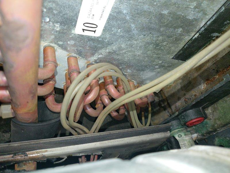 Returned to unit after defrost cycle completed to perform diagnostic evaluation. Upon inspection, found extensive corrosion and oxidation throughout copper refrigerant lines and evaporator coil assembly, indicating prolonged moisture exposure and age-related deterioration. Documented condition of heat exchanger components, insulated refrigerant lines, and internal HVAC system framework showing significant environmental wear and compromised integrity of metal surfaces.