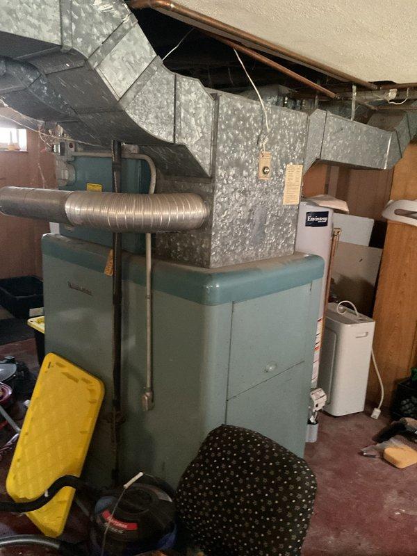Conducted comprehensive site evaluation for complete HVAC system replacement in residential basement installation. Assessed existing teal-colored furnace unit and extensive galvanized sheet metal ductwork configuration for removal and replacement. Evaluated electrical service panel capacity and circuit availability to support new heating and cooling equipment installation. Documented current system layout including flexible metallic duct branches, main trunk line configuration, and clearance requirements for proposed air conditioning addition. Prepared specifications for furnace replacement and new AC system integration with existing duct infrastructure.