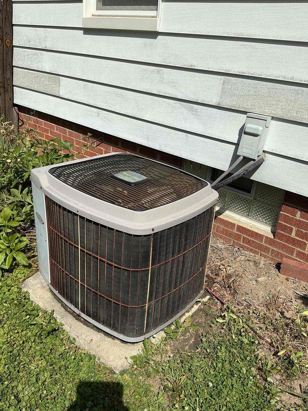 # HVAC Service Completed

Responded to service call for 15-year-old residential air conditioning system not producing cold air. Upon arrival, performed visual inspection of outdoor condenser unit located on concrete pad against exterior wall. Unit appeared to be original equipment with significant age-related wear.

Conducted comprehensive diagnostic evaluation of the system. Checked electrical connections at outdoor disconnect box and verified power supply to condenser. Measured refrigerant pressures and temperatures to assess system charge levels and compressor operation. Inspected condenser coil for blockages and airflow restrictions through protective grille and side louvers. Examined refrigerant line set with foam insulation running from condenser to interior air handler.

Identified multiple issues consistent with aging equipment: low refrigerant charge indicating potential leak in system, reduced compressor efficiency, and debris accumulation around condenser unit affecting heat