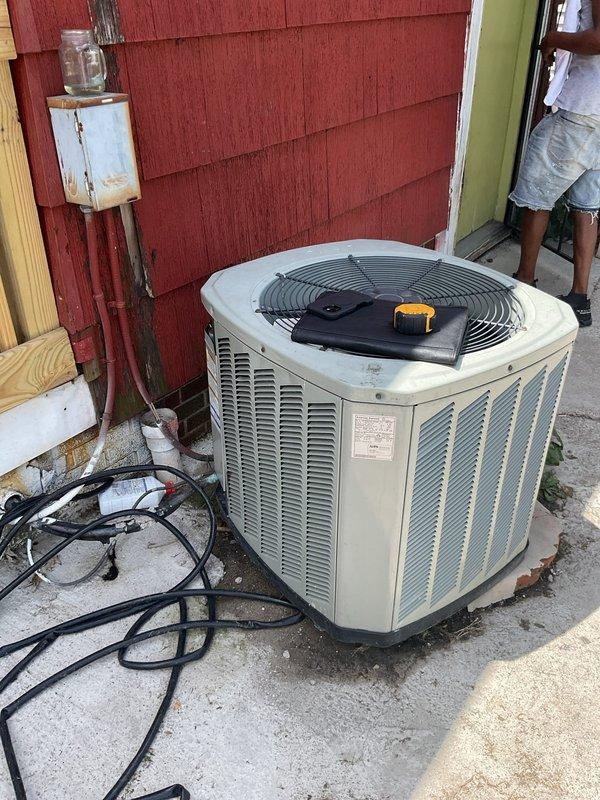 Conducted comprehensive assessment of existing HVAC system for complete replacement estimate. Evaluated outdoor condensing unit positioned on concrete pad adjacent to building exterior, noting beige unit with vertical louvers and top-mounted fan grille with protective covering in place. Inspected electrical disconnect box mounted to structure and associated conduit routing. Documented indoor equipment including Lennox furnace installation located in basement utility area between floor joists. Assessed existing white PVC venting configuration, silver ductwork installation, and overall mechanical space layout. Photographed both outdoor and indoor components to document current system condition and facilitate accurate equipment sizing and replacement specifications for estimate preparation.
