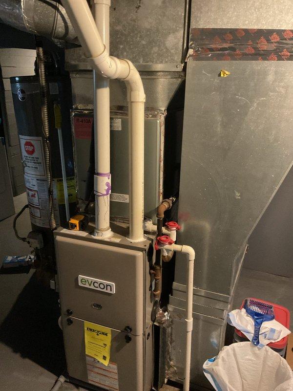 Conducted comprehensive assessment of existing HVAC system for air conditioning replacement. Evaluated current Evcon furnace unit in basement mechanical room, documenting condition of white PVC condensate drainage lines, refrigerant line connections with copper piping and red shut-off valves, and overall system configuration. Inspected outdoor condenser unit positioned against building exterior, noting vegetation encroachment around base and sides that will require clearance for new equipment installation. Photographed existing refrigerant line set with mixed insulation sections running along exterior wall to determine if lines can be reused or require replacement. Assessed electrical connections, condensate drainage routing, and accessibility for equipment removal and new system installation. Provided detailed estimate for complete air conditioning system replacement including outdoor condenser unit and associated components.
