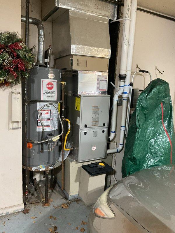 Conducted comprehensive evaluation of existing HVAC system for replacement estimate. Assessed outdoor condenser unit showing significant weathering and age-related deterioration, with unit positioned on grade against exterior brick wall. Documented indoor furnace and associated ductwork configuration in utility area. Captured detailed photographs of both outdoor and indoor equipment to support replacement proposal and system sizing calculations.
