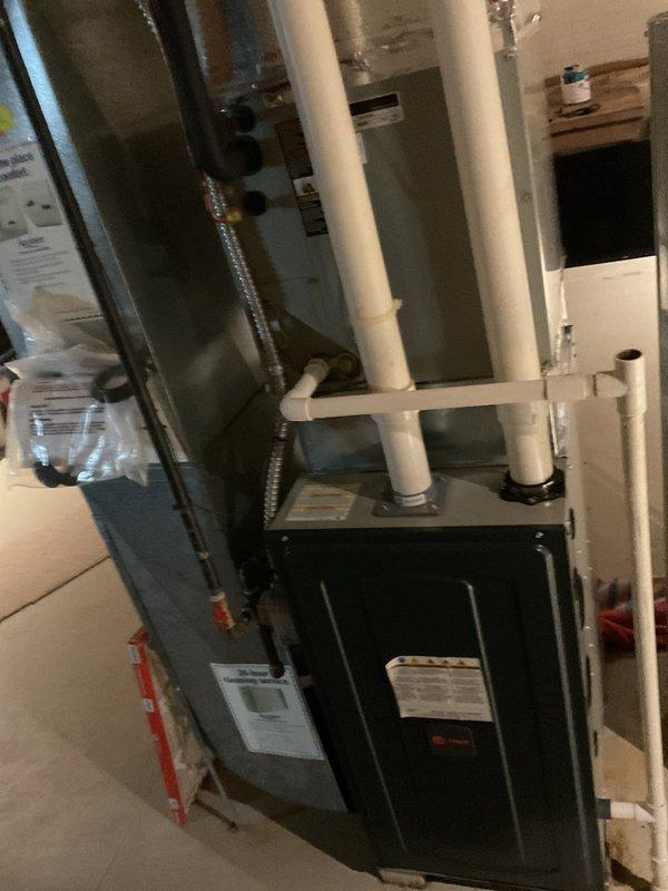 Conducted comprehensive assessment of existing HVAC system for complete replacement estimate. Evaluated outdoor air conditioning condenser unit with light gray casing positioned on concrete pad with proper gravel drainage, noting electrical disconnect box and current unit condition. Inspected indoor furnace and air handler configuration in basement utility area, documenting existing dark-colored furnace with white PVC venting system and metal ductwork components. Performed diagnostic testing using multimeter to assess current system performance and electrical functionality. Photographed existing equipment layout, installation conditions, and spatial requirements for replacement planning. Provided detailed estimate for complete AC system replacement including outdoor condenser unit and necessary modifications to existing infrastructure.