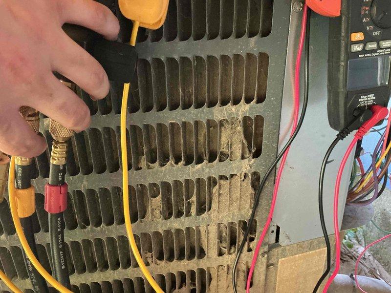 # HVAC Service Report

Responded to service call for 5-year-old air conditioning system displaying "call for service" error message on thermostat. Upon inspection, found outdoor condenser unit with significant dirt and debris accumulation on heat exchanger coils, particularly on one side of the unit. Performed diagnostic testing using multimeter to check electrical components and system operation. Documented unit condition with photos showing contaminated condenser fins requiring cleaning to restore proper airflow and system efficiency.