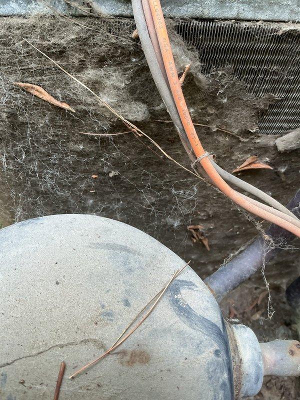 Responded to emergency no-cool call for 1970s-era air conditioning system. Upon inspection, found air handler and evaporator coil severely neglected with extensive accumulation of dust, dirt, debris, and spider webbing throughout the unit and surrounding components. Refrigerant lines showed deteriorated insulation with exposed copper tubing. Blower housing and heat exchanger fins were heavily coated with contaminants, restricting proper airflow and preventing adequate heat transfer. System condition indicated lack of routine maintenance over extended period, resulting in compromised cooling performance and unit failure. Documented equipment condition with photographs showing extent of contamination on evaporator coil, refrigerant lines, blower assembly, and filter compartment. Given the age of the equipment and severity of neglect, advised customer that system requires comprehensive cleaning or replacement to restore proper operation and efficiency.