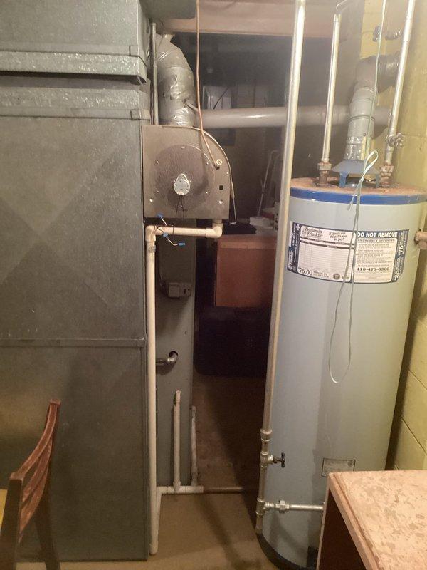 Conducted comprehensive assessment of existing HVAC system located in basement utility area for air conditioning replacement estimate. Evaluated current furnace/air handler unit and associated ductwork configuration to determine compatibility requirements for new AC system installation. Documented existing equipment layout, including proximity to water heater and available clearances for proper airflow and service access. Photographed current system components and mechanical room conditions to support equipment sizing recommendations and identify any necessary modifications to electrical, condensate drainage, or refrigerant line routing for replacement unit installation.