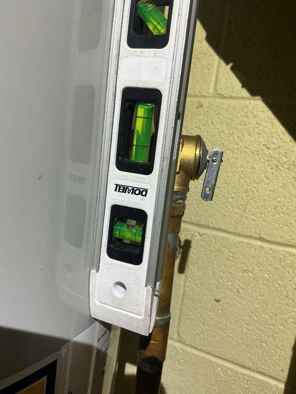Responded to no hot water complaint at 48-year-old residence. Upon inspection, diagnosed failed tanked water heater requiring replacement. Removed old unit and installed new white cylindrical water heater in basement utility area. Connected copper supply lines with proper black foam pipe insulation to prevent heat loss and condensation. Installed recirculation pump with brass fittings at top of tank for improved hot water delivery throughout home. Verified all connections for leaks and proper operation. Used level to ensure tank installation meets manufacturer specifications for optimal performance and longevity. Tested system and confirmed hot water restoration to all fixtures.