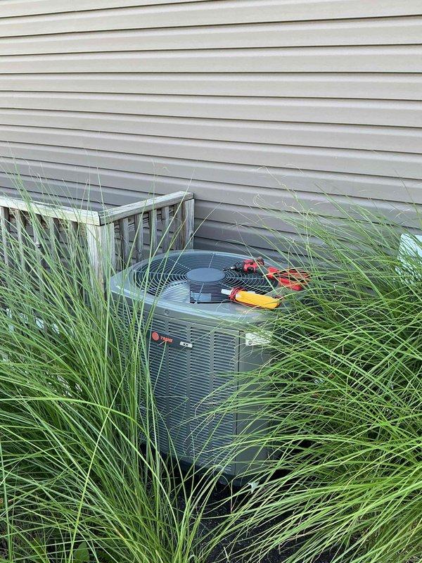 Responded to no-cooling call on 8-year-old XR series air conditioning system. Upon arrival, found condenser unit with significant debris accumulation blocking airflow through coil fins and grilles. Performed diagnostic testing with multimeter to verify electrical components and system operation. Cleaned condenser coils and removed excessive dirt buildup from louvers and ventilation grilles to restore proper airflow. System tested and confirmed operational after cleaning. Recommended ongoing maintenance to prevent future debris accumulation, particularly given proximity to ornamental landscaping.