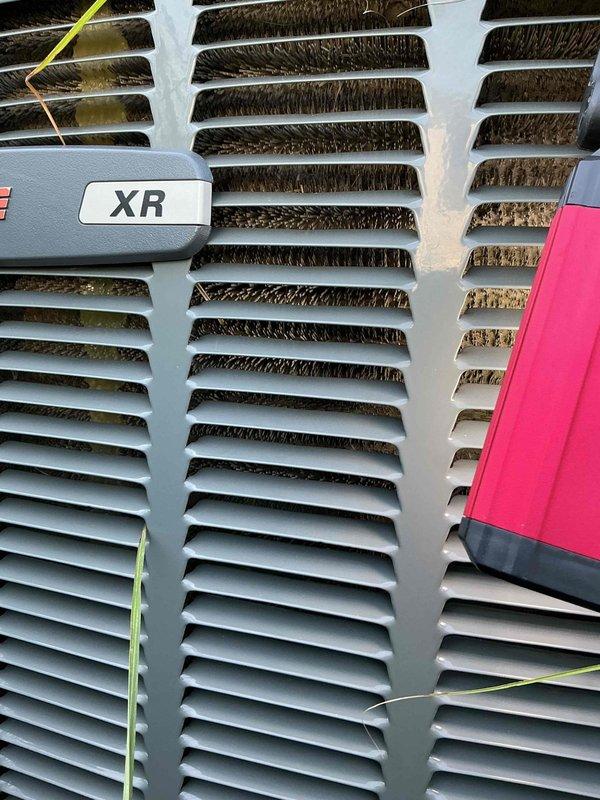 Responded to no-cooling call on 8-year-old XR series air conditioning system. Upon arrival, found condenser unit with significant debris accumulation blocking airflow through coil fins and grilles. Performed diagnostic testing with multimeter to verify electrical components and system operation. Cleaned condenser coils and removed excessive dirt buildup from louvers and ventilation grilles to restore proper airflow. System tested and confirmed operational after cleaning. Recommended ongoing maintenance to prevent future debris accumulation, particularly given proximity to ornamental landscaping.