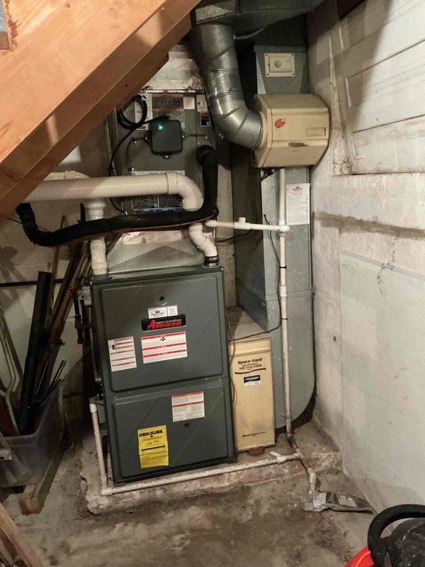 Completed routine maintenance on residential split-system air conditioning unit, including inspection of Amana furnace and air handler located in basement utility area and exterior condensing unit. Performed thorough cleaning of all accessible components, verified proper operation of system controls and thermostat, checked refrigerant levels, inspected electrical connections at disconnect box, and confirmed adequate condensate drainage through PVC piping system. All equipment found to be operating within normal parameters, and photographic documentation was captured of both indoor and outdoor components for service records.