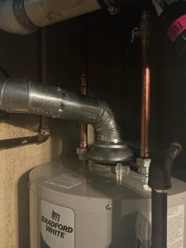 Completed installation of Bradford White tanked water heater in residential basement utility room. Connected all required plumbing components including copper supply lines and PVC piping, installed galvanized metal exhaust venting with proper elbow configuration, and verified level placement of unit. All connections tested and system confirmed operational.