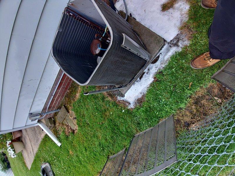 Performed routine cooling maintenance on a 10-year-old residential air conditioning system. Removed access panel to inspect internal components including condenser coils, refrigerant lines, and electrical connections, confirming all systems were operating properly. Unit and surrounding area photographed for service documentation.