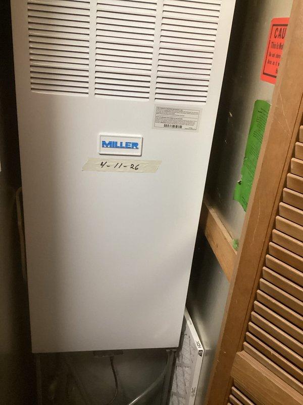 Completed estimate for replacement of existing Miller brand HVAC system. The current unit is a cabinet-style heating and cooling system installed in an interior closet space, with manufacturing date indicating 1986 installation. Assessed equipment condition, measured existing ductwork and ventilation components including louvered return air grille, and documented system configuration with photographs for replacement proposal preparation.