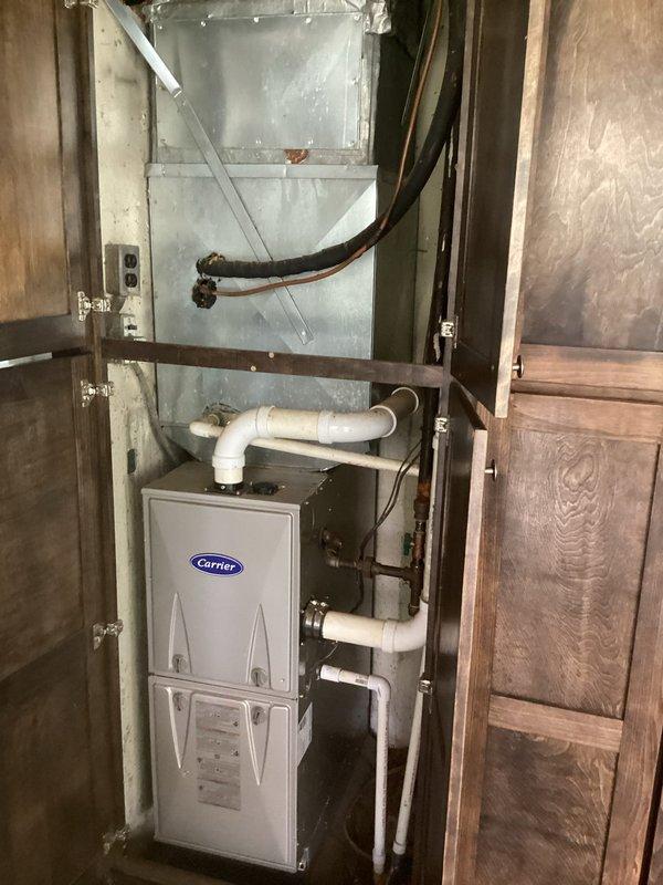 Completed comprehensive evaluation of existing HVAC system for full replacement estimate. Assessed outdoor Carrier condenser unit with cylindrical design and protective grille, noting current installation positioning adjacent to exterior wall with existing electrical infrastructure including dual meter panels and conduit routing. Evaluated indoor Carrier furnace system housed within utility closet enclosure, inspecting existing ductwork plenum, PVC condensate drainage configuration with proper trap installation, and flexible duct connections. Documented equipment specifications, spatial constraints, electrical service capacity, and installation accessibility to provide accurate replacement system recommendations and ensure proper sizing for residential comfort requirements.