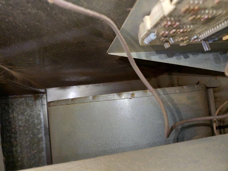 Responded to service call for noisy blower motor on aging furnace system estimated at over 20 years old. Upon inspection, identified worn blower fan bearings as source of operational noise. Documented existing equipment condition with photos showing motor assembly with visible wear, paint deterioration, and flexible conduit connections, as well as internal cabinet components including ductwork and evaporator coil assembly. Customer advised of findings and equipment age considerations for future planning.