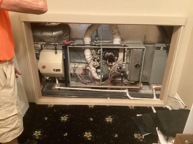 Conducted comprehensive assessment of existing HVAC system for complete furnace and air conditioning replacement. Evaluated outdoor octagonal condenser unit positioned on concrete pad against exterior wall, documenting current equipment condition and installation parameters. Inspected interior mechanical compartment containing furnace, air handler, expansion tank, and associated ductwork, PVC piping, electrical connections, and control boards to determine specifications for replacement equipment and identify any modifications required for new system installation.