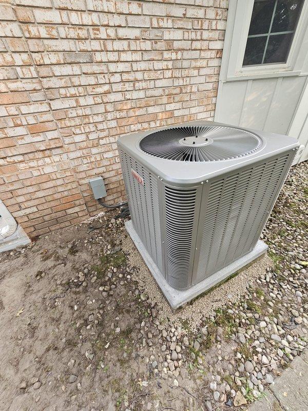 # HVAC System Installation

Completed full air conditioning system installation including outdoor condenser unit and upflow cased evaporator coil. Installed new condenser on white concrete equipment pad with proper gravel base for drainage. Ran new refrigerant lineset with insulated copper tubing and connected all refrigerant lines to unit with brass fittings and service valves. Installed new electrical disconnect box and whip to unit mounted on exterior brick wall with proper conduit routing. Configured system for upflow application within 30-inch clearance requirement and installed necessary ductwork transitions. Installed new thermostat for system control. System tested and operational with 10-year parts and labor warranty coverage.
