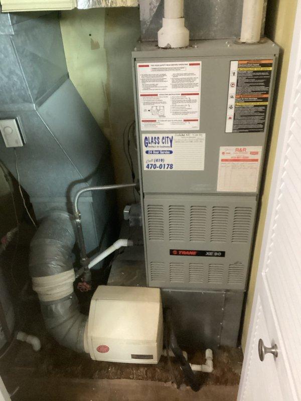 Conducted comprehensive on-site evaluation for complete HVAC system replacement involving existing Trane XE 90 furnace and outdoor air conditioning condenser unit. Assessed current equipment configuration, including indoor furnace installation with connected humidifier, ductwork connections, PVC venting system, and outdoor condensing unit mounted on concrete pad with electrical disconnect and refrigerant line routing. Documented existing system specifications, installation conditions, and spatial requirements to prepare detailed replacement estimate per previous coordination.
