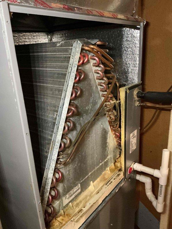 Responded to service call regarding water accumulation around furnace base and air filter installation issue. Upon inspection, accessed evaporator coil assembly and identified condensate drainage concern. Examined HVAC system components including evaporator coil with copper tubing, condensate drain lines with PVC piping, and furnace unit. Documented system condition showing signs of normal operational wear and verified proper access to internal components for maintenance. Investigated filter compartment alignment issue and assessed overall system functionality.