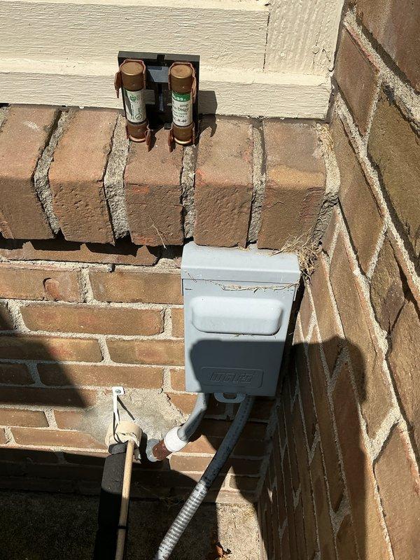 # HVAC Cooling Maintenance Completed

Performed comprehensive cooling system maintenance on residential HVAC unit. Conducted thorough inspection of outdoor condensing unit and associated electrical components mounted on exterior brick wall. 

Inspected and verified proper operation of outdoor disconnect box and cartridge-style fuse assembly. Both fuses showed clear markings and appeared to be functioning within normal parameters. Weatherproof electrical enclosure was secure with no signs of moisture intrusion or physical damage.

Utilized clamp meter to measure electrical current draw on system control wiring and power conductors. Verified amperage readings on multiple wire circuits including control wires to ensure system was operating within manufacturer specifications. All electrical connections were tight and properly secured.

Examined flexible conduit routing and wire management at outdoor unit location. Inspected brass fittings and connections for signs of corrosion or wear. All