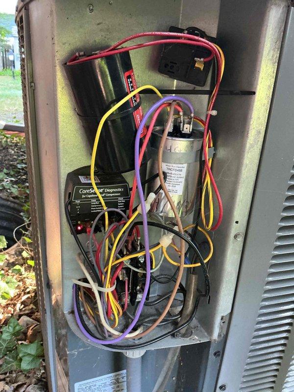 Completed comprehensive air conditioning tune-up on 11-year-old outdoor unit. Performed standard maintenance procedures including inspection of capacitor, electrical connections, and CoreSense diagnostic system; all components found operating within normal parameters despite visible exterior weathering and organic growth on housing surfaces typical of outdoor installation.