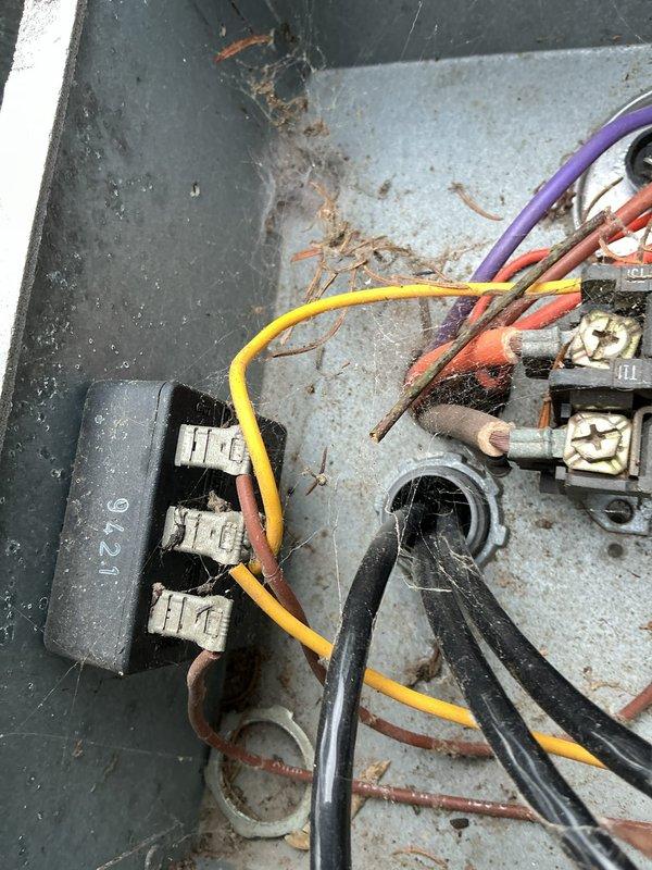 # HVAC Service Report

Responded to no cooling complaint affecting entire residence with 20-year-old air conditioning system. Upon arrival, performed diagnostic evaluation of outdoor condensing unit and electrical components.

Utilized digital clamp meter to measure electrical amperage on refrigerant lines, recording reading of 16.1 amps. Inspected compressor unit showing significant age-related wear, including surface corrosion on copper refrigerant lines and accumulated debris around equipment base. Outdoor unit positioned on concrete pad with visible deterioration and environmental exposure.

Opened and inspected electrical junction box revealing multiple wire connections with signs of aging. Observed terminal block component #6216 with various colored wire connections including yellow, purple, orange, black, and brown conductors. Noted visible corrosion, debris accumulation, and organic material within electrical enclosure, indicating prolonged exposure to outdoor elements. Termina