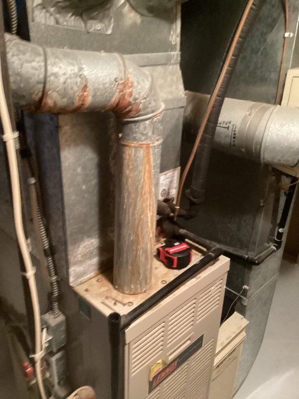 Completed comprehensive assessment of existing HVAC system for air conditioning replacement estimate. Documented current equipment configuration including furnace, humidifier unit with integrated controls, and existing ductwork system. Inspection revealed significant rust and corrosion throughout metal ductwork, particularly at joints and seams of upper plenum and vertical supply connections, indicating moisture exposure and age-related deterioration. Evaluated complete system layout in basement mechanical room, noting copper refrigerant lines, flexible duct connections, and overall equipment placement. Photographed existing installation to document pre-replacement conditions and identify scope of work required for AC system upgrade. Provided detailed estimate for air conditioning replacement based on current system assessment and observed equipment conditions.