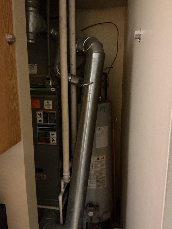 Responded to service call for leaking water heater. Upon arrival, inspected 10-year-old residential tanked water heater located in utility closet alongside HVAC equipment. Conducted visual assessment of unit and surrounding plumbing connections to identify source of leak. Documented existing conditions including water heater installation, associated piping (copper supply lines, PVC drainage, and metal flue vent), and evidence of moisture or water damage. Photographed equipment configuration and closet layout for service records. Provided assessment findings and recommended next steps for leak repair or unit replacement based on age and condition of water heater.