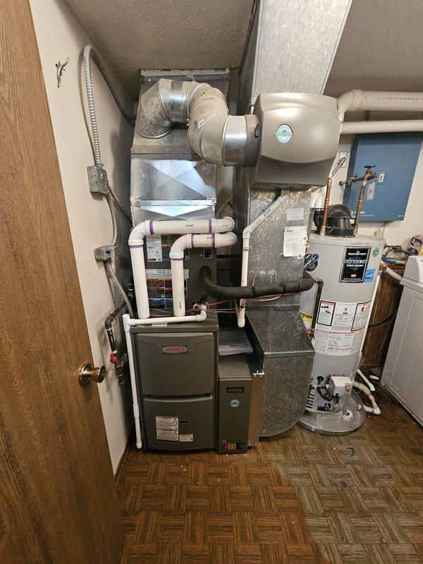 Completed full HVAC system replacement including installation of Lennox 96% AFUE 70,000 BTU upflow gas furnace with AHRI #215587047 certification, matched upflow cased evaporator coil, and single-stage air conditioning condenser unit. Installed new 3/4" x 15' refrigerant line set with proper insulation, fabricated and mounted metal 5" filter rack for improved air filtration, and ran 20 feet of 2" PVC condensate drain piping with proper pitch and termination. Added 12-gallon whole-home humidifier integrated with ductwork, placed condenser on new equipment pad with level verification, installed electrical disconnect and whip for outdoor unit per code requirements, and upgraded to new programmable thermostat with system configuration and testing to ensure proper heating and cooling operation.
