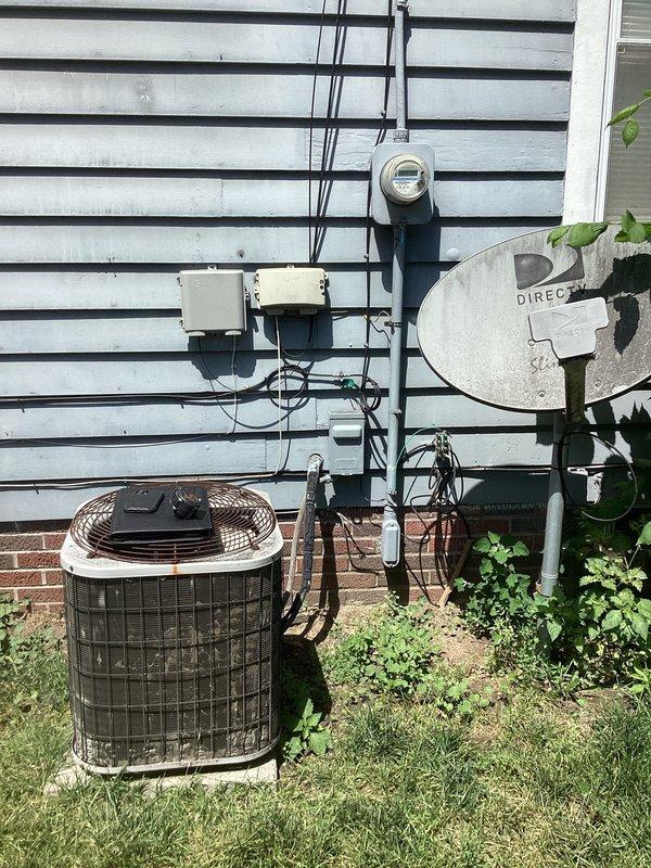 Conducted comprehensive site assessment for complete HVAC system replacement at residential rental property. Evaluated existing outdoor condensing unit with protective cage enclosure positioned on concrete pad adjacent to building foundation, noting electrical service connections and meter configuration. Inspected basement mechanical room containing Gibson furnace with associated ductwork, including flexible insulated ducting and rigid metal supply/return piping. Documented current system layout, electrical infrastructure, refrigerant line routing, and existing copper plumbing connections to provide accurate replacement specifications and equipment sizing recommendations for property management consideration.