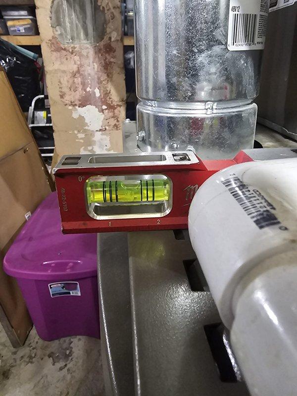 Corrected improper furnace installation from previous contractor by adjusting unit to proper slope toward condensate drain. Unit had been incorrectly sloped away from drain for approximately one year. Releveled furnace using concrete blocks and rubber pads as shims, verified correct pitch with spirit level to ensure proper condensate drainage and prevent future water damage or system issues.