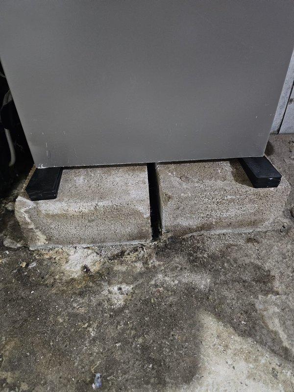 Corrected improper furnace installation from previous contractor by adjusting unit to proper slope toward condensate drain. Unit had been incorrectly sloped away from drain for approximately one year. Releveled furnace using concrete blocks and rubber pads as shims, verified correct pitch with spirit level to ensure proper condensate drainage and prevent future water damage or system issues.