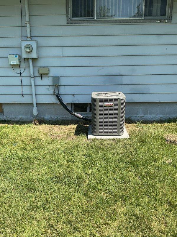Completed retrofit installation of new air conditioning system on existing furnace in basement location. Installed upflow cased A-coil in cabinet configuration, mounted new single-stage condenser unit on pad approximately 3 feet from electrical meter, and ran new 3/4-inch lineset 30 feet from outdoor unit to indoor coil. Installed new disconnect box and whip for condenser unit, routed refrigerant lines through foundation, and installed new thermostat to control system operation. All electrical connections completed per code requirements with proper conduit installation visible on exterior wall.