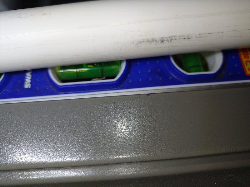 Responded to water leak reported at back of air conditioning unit that developed following recent service visit. Upon arrival, inspected Lennox air handler and associated condensate drainage system. Used level to verify proper pitch on horizontal PVC condensate drain line. Investigated potential causes including condensate pan issues, drain line blockages, or installation concerns related to previous service. Documented system configuration with photographs showing vertical PVC venting, condensate piping, and overall unit installation. Verified drain line connections and assessed whether leak was related to prior service work or separate issue requiring additional repair.