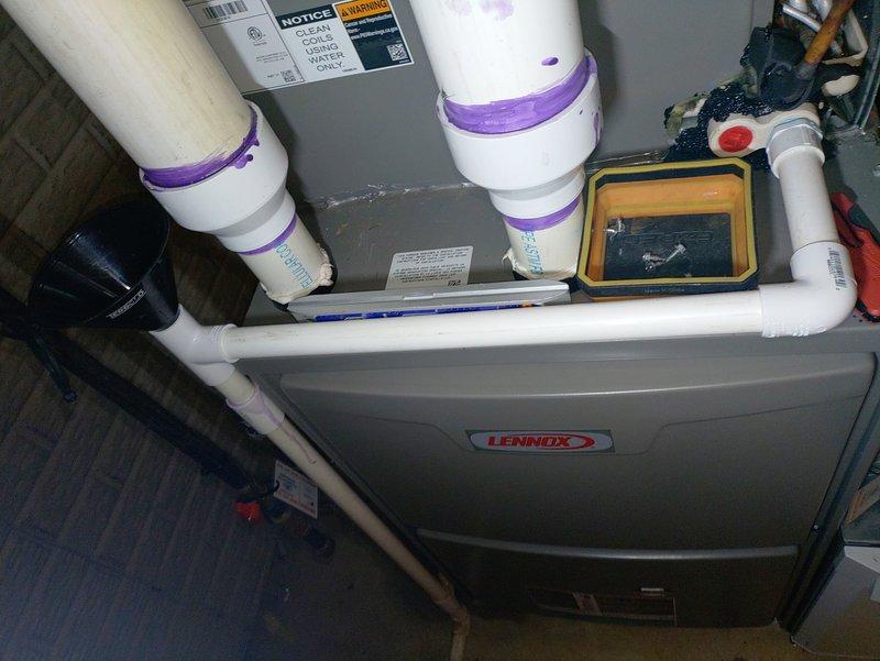 Responded to water leak reported at back of air conditioning unit that developed following recent service visit. Upon arrival, inspected Lennox air handler and associated condensate drainage system. Used level to verify proper pitch on horizontal PVC condensate drain line. Investigated potential causes including condensate pan issues, drain line blockages, or installation concerns related to previous service. Documented system configuration with photographs showing vertical PVC venting, condensate piping, and overall unit installation. Verified drain line connections and assessed whether leak was related to prior service work or separate issue requiring additional repair.