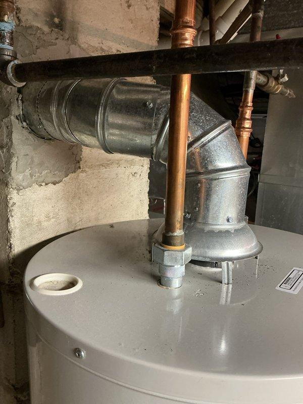 Completed inspection corrections on HVAC installation. Installed locking-type caps on condenser unit per code requirements. Corrected hot water tank exhaust venting by securing all joints with three screws each to meet inspection standards. Documentation photos provided to inspector for approval.