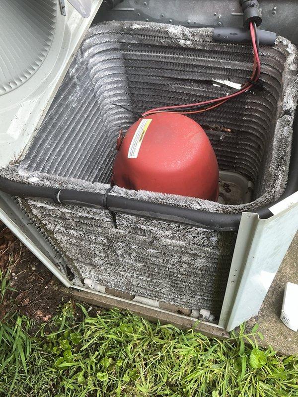 Responded to emergency no-cooling call on residential air conditioning unit approximately 15 years old. Upon arrival, confirmed thermostat set to 72°F while indoor temperature measured 80°F. Inspection revealed outdoor condenser unit with severely restricted airflow due to heavy accumulation of dirt, dust, lint, and debris coating the condenser coil fins. Removed top panel to access internal components and documented condition of coil assembly and refrigerant line insulation showing significant weathering and deterioration. The outdoor unit exhibited normal operational wear consistent with age, but debris buildup on coil surfaces was substantially impacting heat transfer efficiency and system performance. Recommended thorough coil cleaning and system evaluation to restore proper cooling capacity.