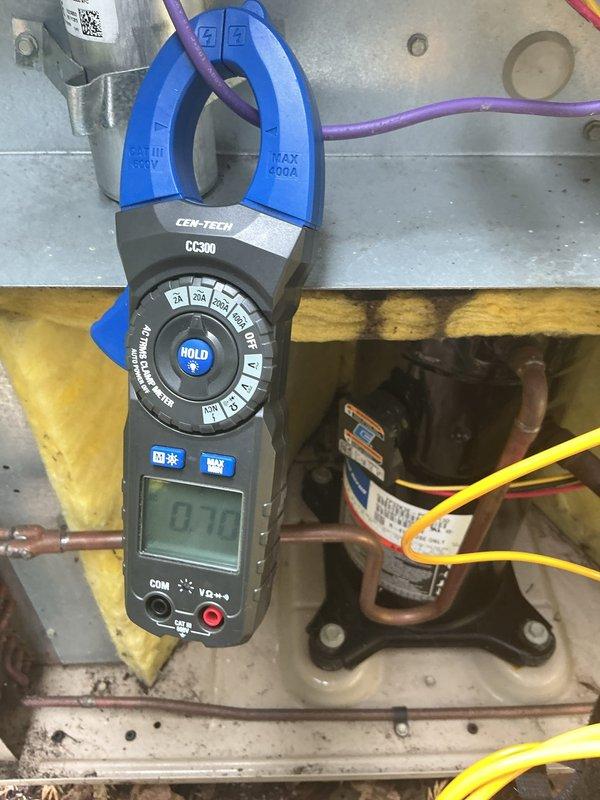 # HVAC Service Report

Responded to no cooling complaint on 22-year-old residential air conditioning system. Upon arrival, confirmed unit was not operating and producing no cool air. Visual inspection revealed compressor and outdoor unit components showed significant age-related wear and environmental deterioration.

Performed electrical diagnostics using clamp meter to measure amperage draw on compressor circuit. Readings indicated minimal current flow at 0.12 amps, well below normal operating parameters for compressor operation. Inspected high-pressure safety switch mounted on refrigerant lines, which appeared to be in tripped position based on visual assessment of reset button.

Examined copper refrigerant line connections and found evidence of outdoor unit exposure to moisture and debris accumulation on concrete pad. Dead leaves and organic material had collected around base of unit, and moss growth was present on surrounding surfaces, indicating prolonged exposure to damp conditio