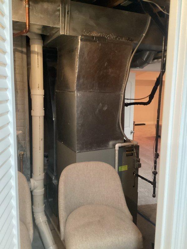 Completed comprehensive estimate for full HVAC system replacement at residential property. Evaluated existing indoor air handler unit located in utility closet showing significant dust accumulation and aging components, along with outdoor condensing unit positioned in exterior corner area on mulch bed. Assessment included inspection of current ductwork configuration with flexible metallic connections, existing PVC condensate drainage system, electrical connections, and thermostat controls to determine complete replacement specifications and equipment requirements for new high-efficiency system installation.