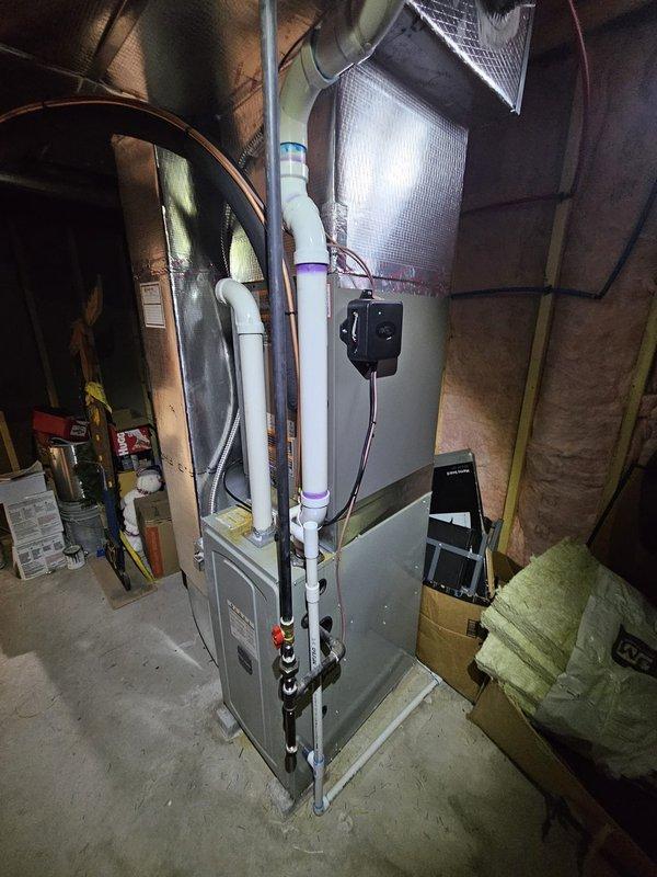 Completed installation of a new Lennox air conditioning package system including outdoor condenser unit and indoor evaporator coil. Positioned the condenser unit on a concrete pad adjacent to the building exterior with proper clearances for airflow and service access. Inside the mechanical room, installed the evaporator coil assembly integrated with the existing furnace system, complete with insulated ductwork connections and proper refrigerant line routing. Ran copper refrigerant lines with white insulation from the outdoor unit to the indoor coil, ensuring proper pitch and support. Installed PVC condensate drain lines with appropriate fittings and slope for proper drainage. Made all electrical connections including power supply to the condenser unit and control wiring between indoor and outdoor components. Pressure tested the refrigerant system, evacuated to manufacturer specifications, and charged with the correct refrigerant type and quantity. Verified all electrical connections, t