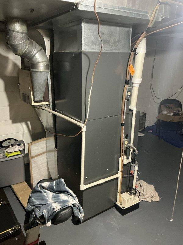 Responded to service call for water accumulation under furnace in basement. Upon inspection, identified condensate drainage issue originating from upper section of condensate line assembly. Examined condensate pump system, PVC drain line configuration with P-trap, and associated connections to furnace air handler unit. Traced source of water leak to compromised connection point at top portion of condensate hose where it interfaces with primary drain line. Verified condensate pump operation and cleared any blockages in drainage system. Secured all connections, tested system operation under normal condensing conditions, and confirmed proper drainage flow with no further leakage detected.