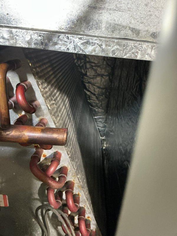 Completed routine maintenance tune-up on 10-year-old residential air conditioning system. Upon inspection, discovered significant frost and ice accumulation on evaporator coils and metal surfaces within the air handler unit, indicating restricted airflow or potential refrigerant issues. Documented internal components including copper refrigerant lines, evaporator coil assembly, condensate drain line, and service valves for maintenance records.