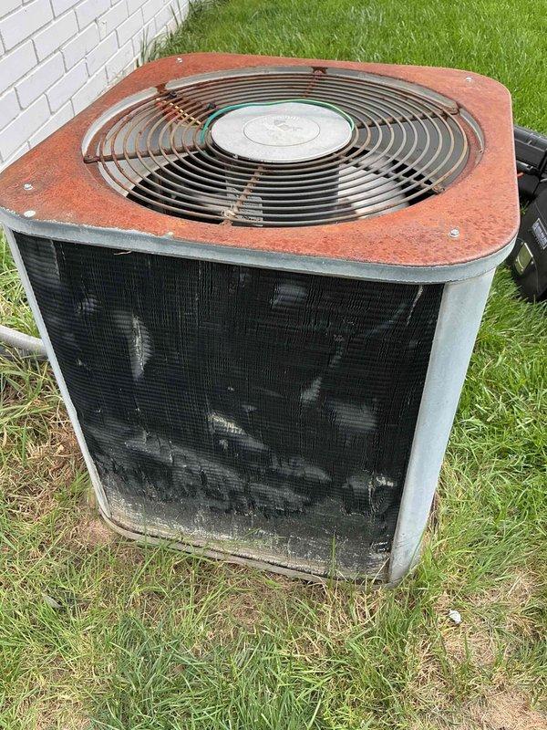Responded to service call for outdoor condensing unit producing loud scraping metal noise while fan motor was running. Upon inspection, found aged unit with severely corroded top panel and fan grille assembly showing extensive rust and oxidation damage. Identified source of noise as debris interference or bearing failure in condenser fan motor assembly, causing metal-on-metal contact during operation. Documented equipment condition with photos showing significant weathering, deteriorated coil fins with accumulated dirt and debris, and overall aging of unit components requiring attention.