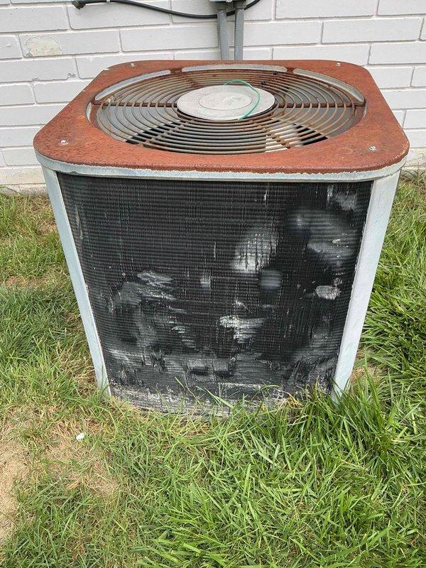 Responded to service call for outdoor condensing unit producing loud scraping metal noise while fan motor was running. Upon inspection, found aged unit with severely corroded top panel and fan grille assembly showing extensive rust and oxidation damage. Identified source of noise as debris interference or bearing failure in condenser fan motor assembly, causing metal-on-metal contact during operation. Documented equipment condition with photos showing significant weathering, deteriorated coil fins with accumulated dirt and debris, and overall aging of unit components requiring attention.