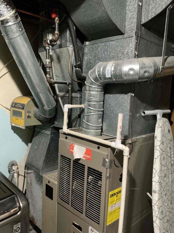 Responded to no cooling complaint on 15-year-old air conditioning system. Found ice formation on exterior refrigerant lines and moisture present on interior line, indicating restricted airflow or low refrigerant charge. Customer had turned system off overnight prior to service call. Inspected air filter which was replaced in July but noted system age of approximately 15-16 years. Evaluated HVAC equipment installation including furnace unit, ductwork connections, and associated mechanical components in utility space. Documented system condition and advised customer on findings related to ice buildup and cooling performance issues.