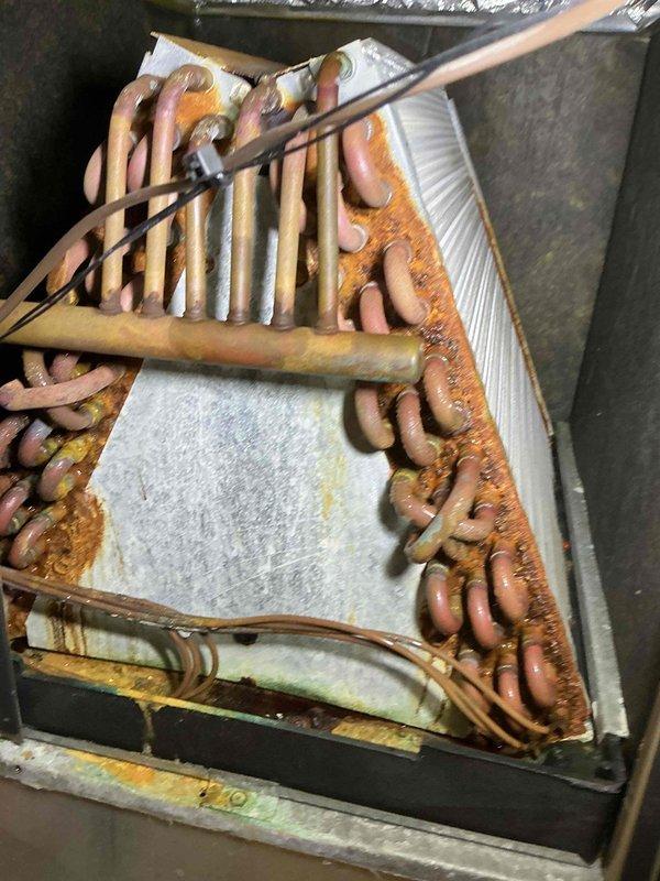 Completed standard tune-up maintenance on 15+ year old residential air conditioning system during scheduled service window. Performed comprehensive inspection of evaporator coil assembly, which revealed significant age-related deterioration including heavy copper tube oxidation, aluminum fin corrosion, and visible structural degradation throughout the A-frame coil configuration. Documented equipment condition with photographic evidence showing extensive rust patina on refrigerant lines and moisture damage indicators. System operational at time of service completion, though advanced component wear suggests consideration for future replacement planning due to compromised coil integrity and overall unit age.
