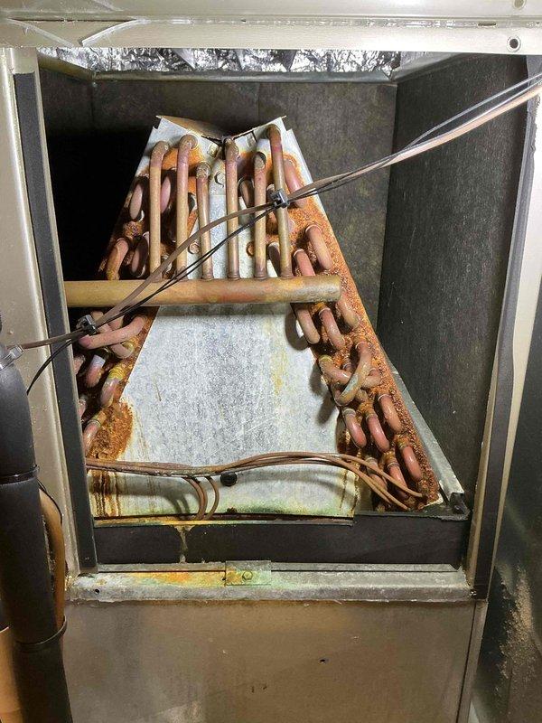 Completed standard tune-up maintenance on 15+ year old residential air conditioning system during scheduled service window. Performed comprehensive inspection of evaporator coil assembly, which revealed significant age-related deterioration including heavy copper tube oxidation, aluminum fin corrosion, and visible structural degradation throughout the A-frame coil configuration. Documented equipment condition with photographic evidence showing extensive rust patina on refrigerant lines and moisture damage indicators. System operational at time of service completion, though advanced component wear suggests consideration for future replacement planning due to compromised coil integrity and overall unit age.