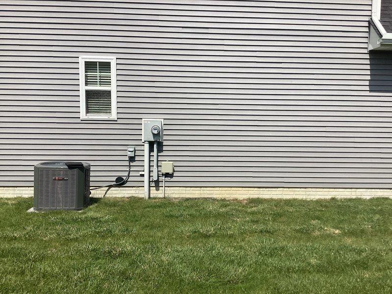 Conducted on-site assessment for mini split system installation in a basement living area and evaluated exterior wall mounting location. Documented interior space layout and existing HVAC infrastructure including outdoor condenser unit positioning, electrical service panel, and available wall space for indoor air handler placement.